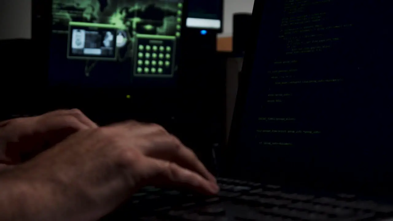 Computer hacker working in shadowy backroom coding