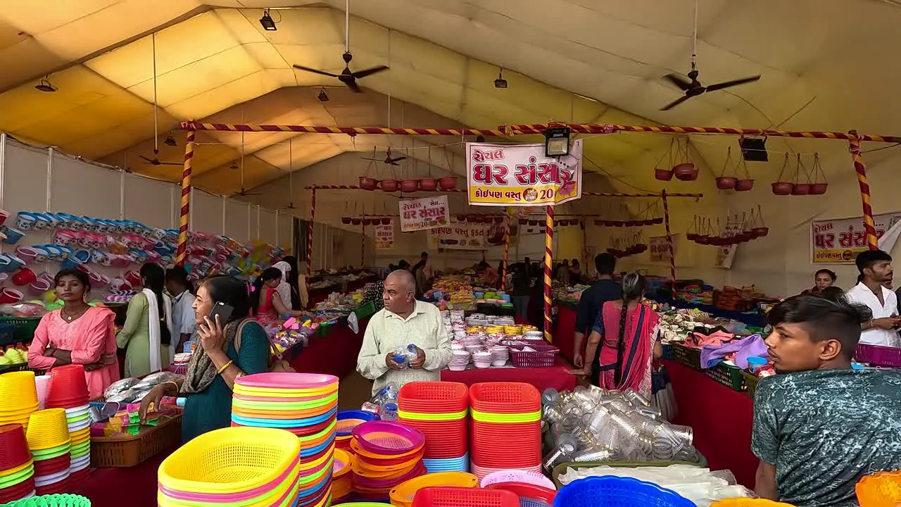 There is a sale of household utensils made of plastic and steel and women are buying them