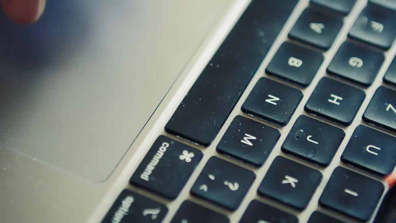 Fingers using touchpad on mac computer with dirt on the keyboard close up