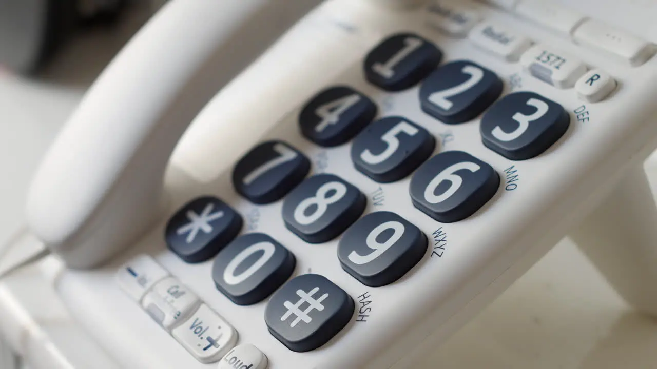 Close up of a man dialling 999 on a telephone