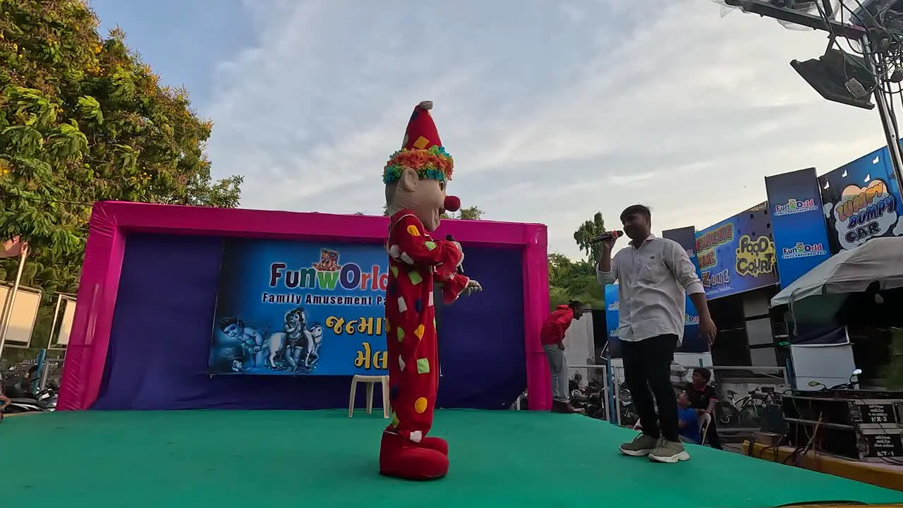 A clown joker in an amusement park is entertaining young children wearing a joker clown costume