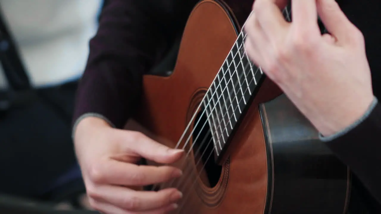 Detail of a classical guitar and male hands playing on it