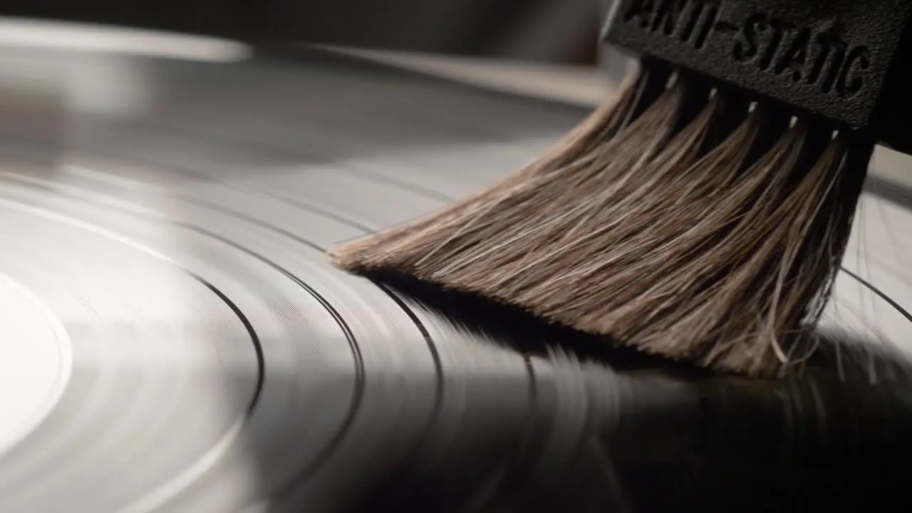 Hand removing dust from a vinyl record with antistatic brush