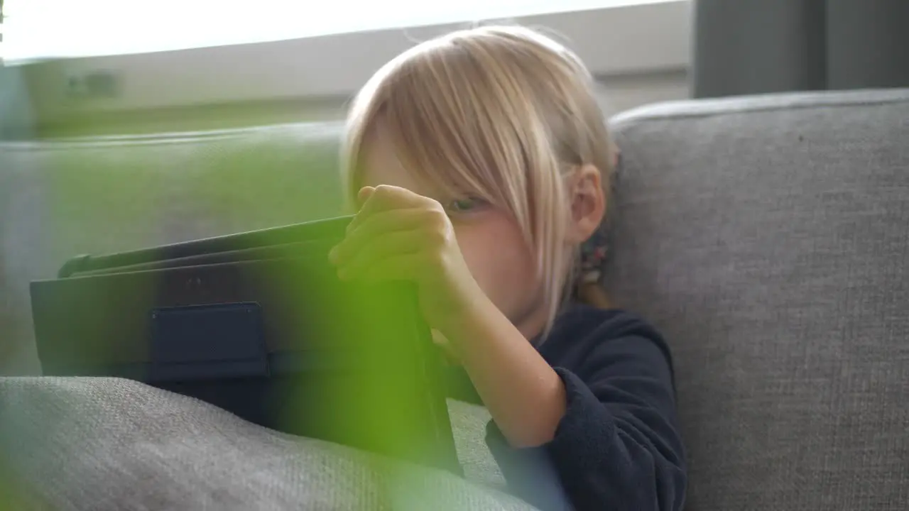 Little girl uses tablet at home on couch slider shot