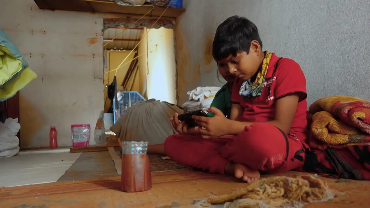 Young Indian Boy and Sister Sit Absorbed in Online Streaming Video on Smartphone