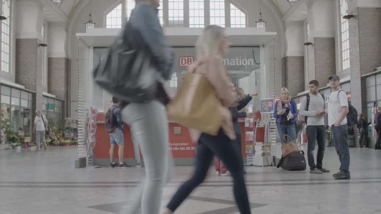 Passengers at a train station information desk possibly seeking guidance for their travel plans