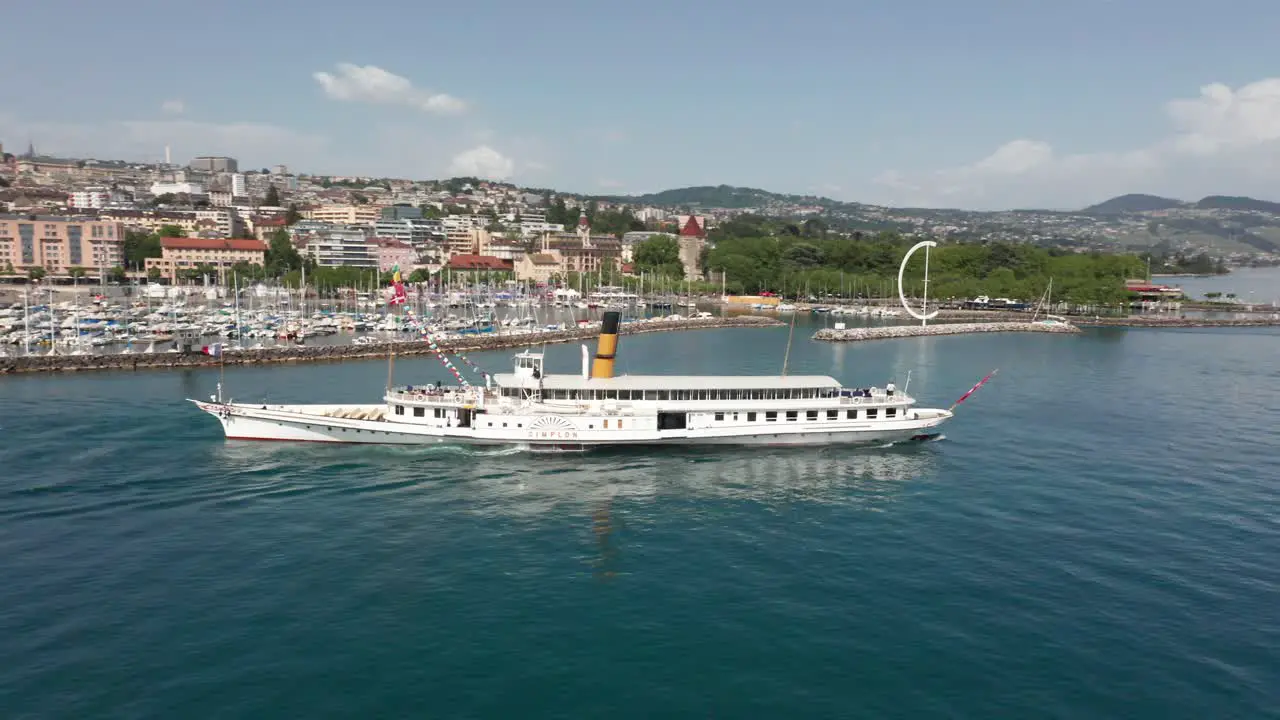 Aerial of beautiful old cruise ship leaving harbor with a city in the background