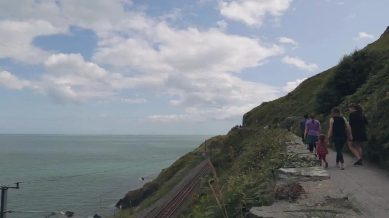 People hiking along a railway on the coast on a sunny day