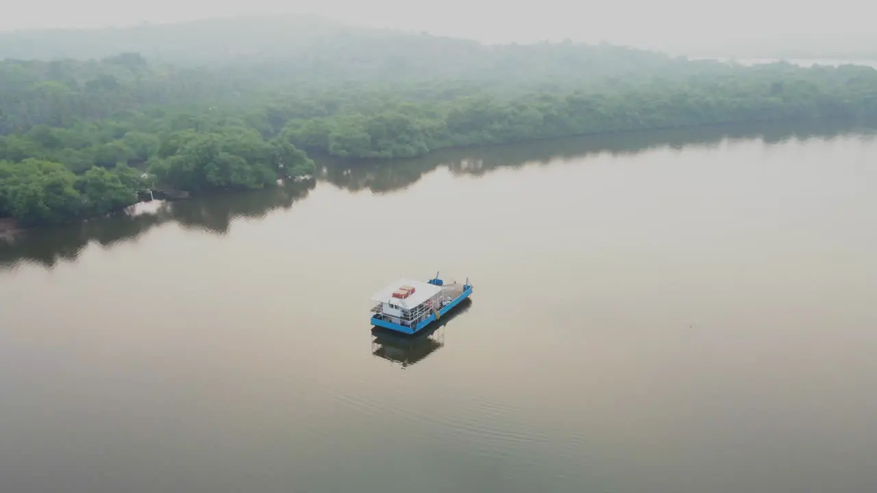 ship boat in still river India goa divar island Panjim drone morning fog sunset foggy weather orbital shot