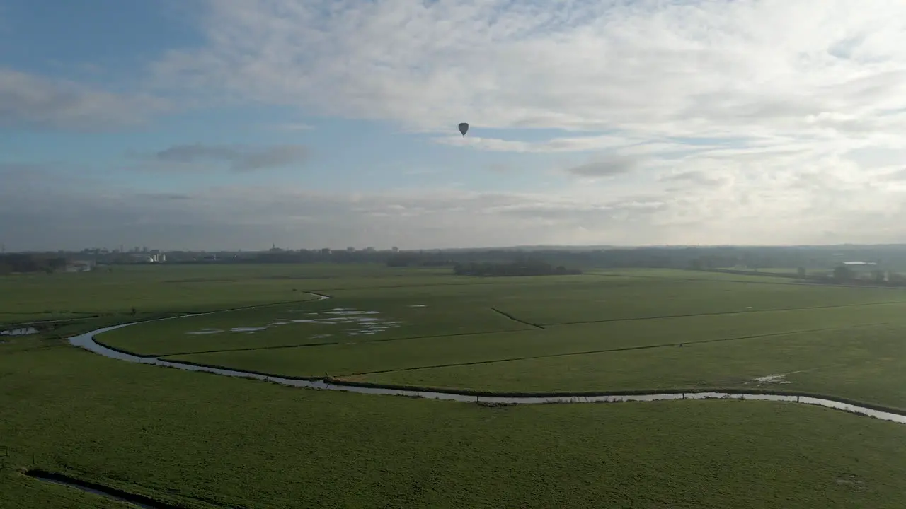 Aerial jib up of beautiful dutch landscape with a hot air balloon in the distance