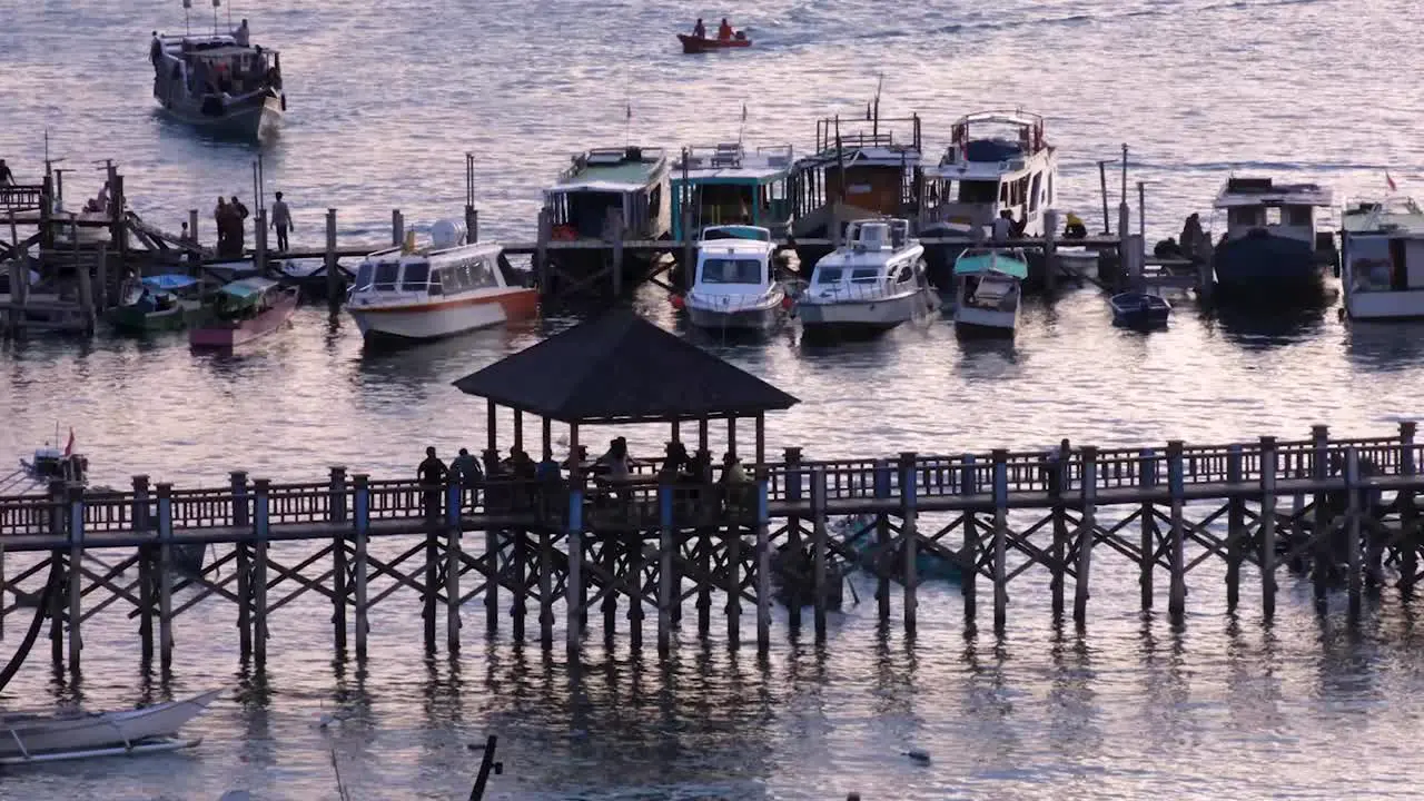 People gathering and mingling on jetty at Labuan Bajo harbour and ocean during evening twilight sunset in Flores Island Indonesia