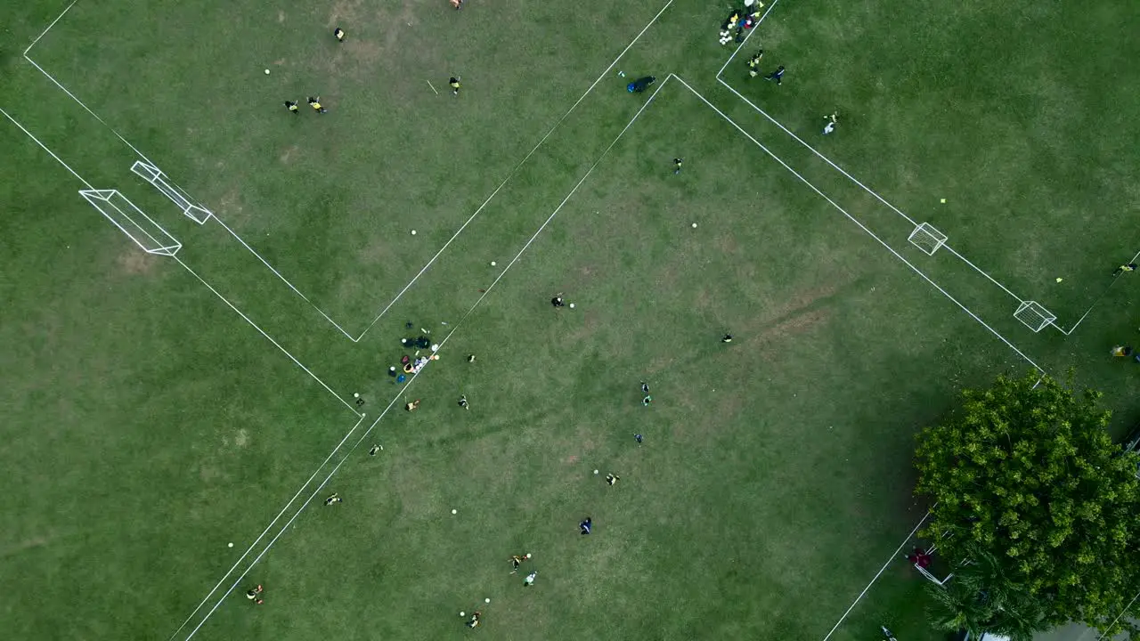 Aerial top down view of men training football on grass soccer field