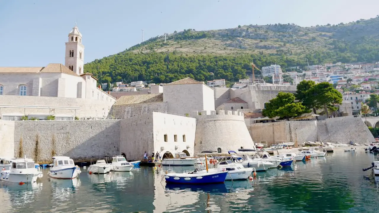 Dubrovnik yachts anchored in the harbor with city buildings and a clock tower in the background