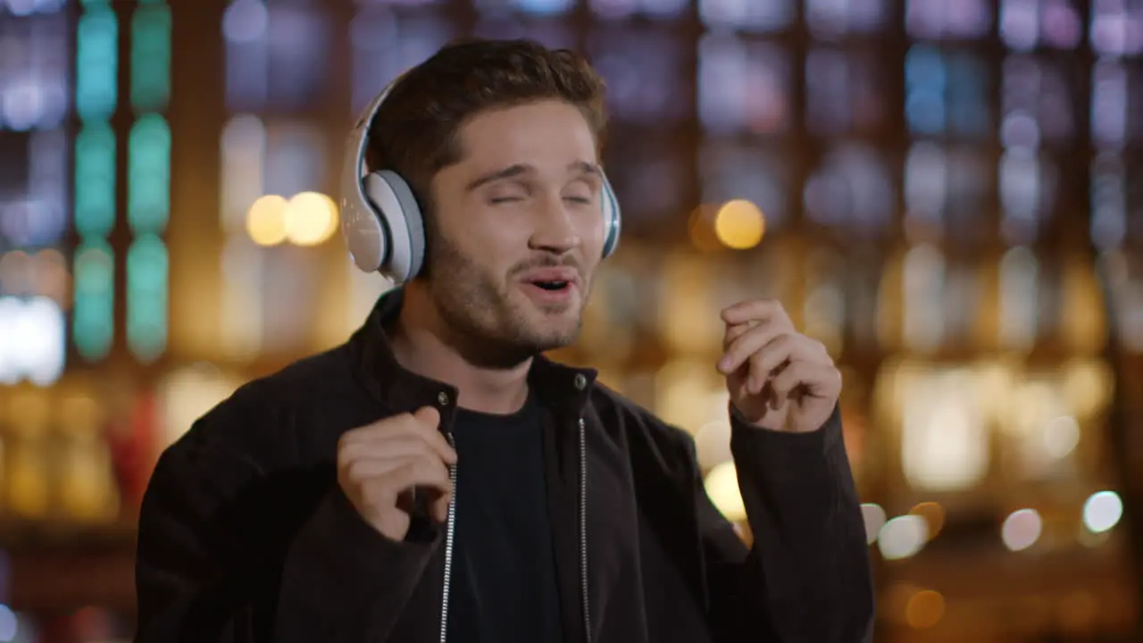 Excited man enjoying music headphones on street Euphoric guy dancing outdoors