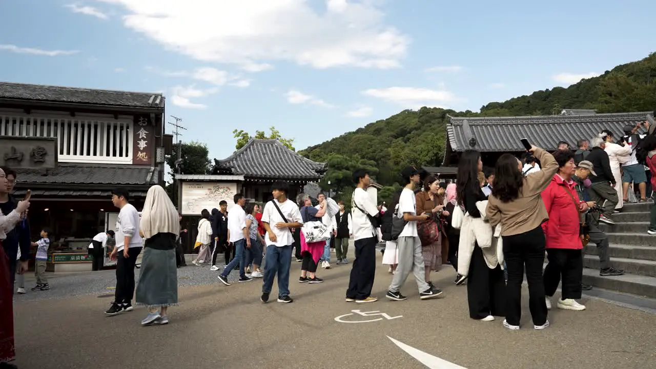 Large group of tourists traveling and visiting the roads and streets of an ancient temple in Japan learning about its architecture culture and history