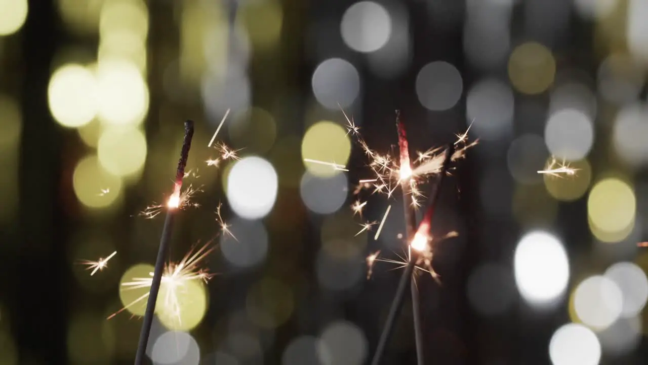 Video of close up of sparklers with bokeh and copy space on black background