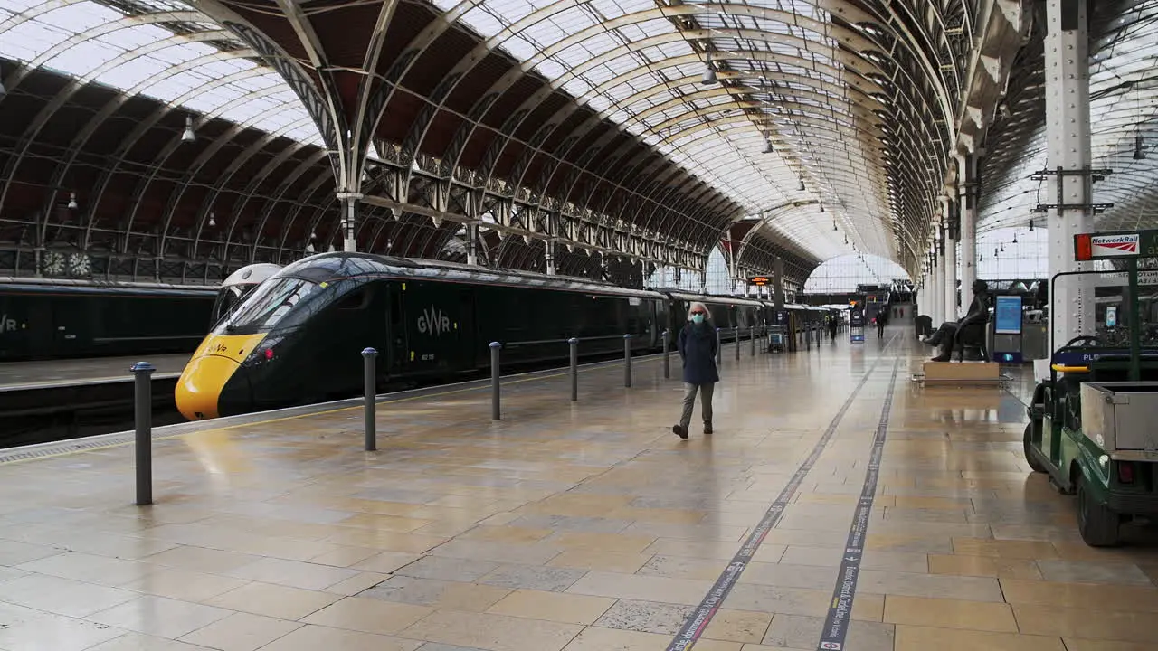 One person walking wearing face mask covering in Paddington Train Station during Coronavirus Covid-19 lockdown in London when public transport was quiet and deserted with no people in England Europe