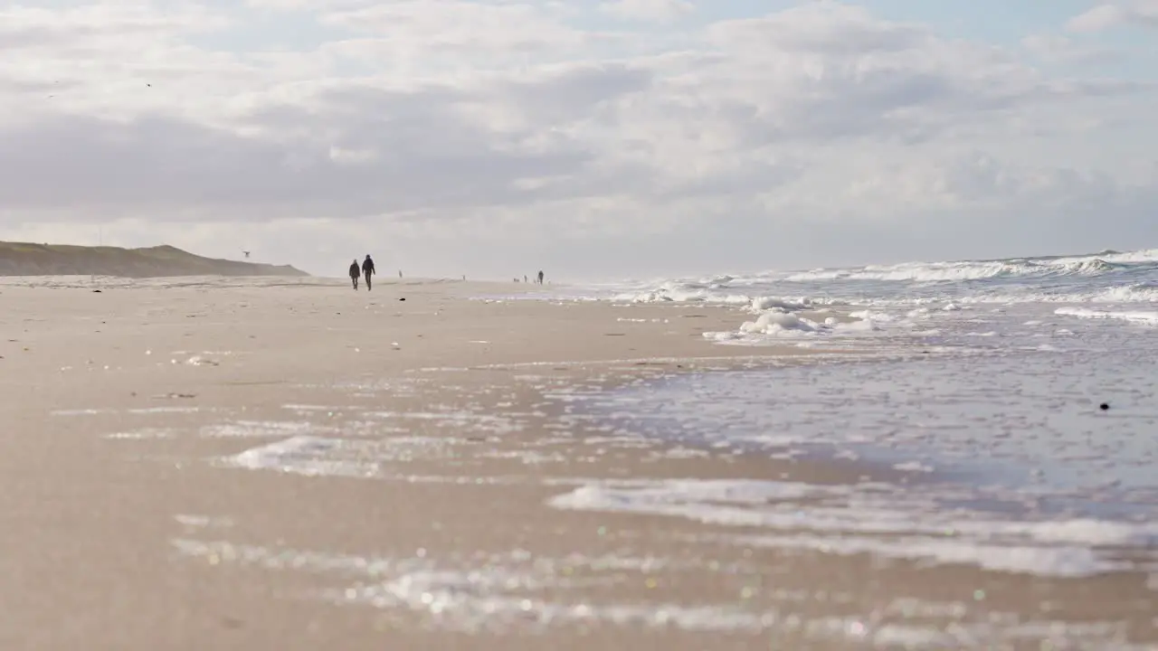 Silhouettes of couple walking in slow motion on sandy Sylt beach in Germany