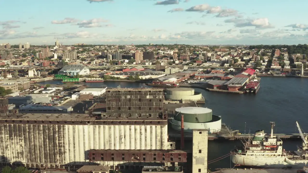 Stationary aerial shot of the massive abandoned grain terminal and an rusty ship nearby in Brooklyn New York