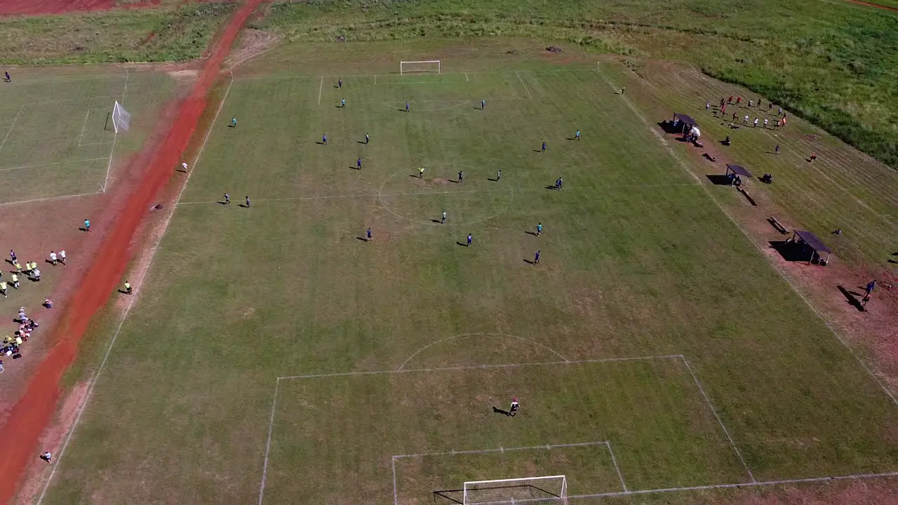 Drone orbit around football players walking onto pitch revealing other nearby football pitches players train on the side line