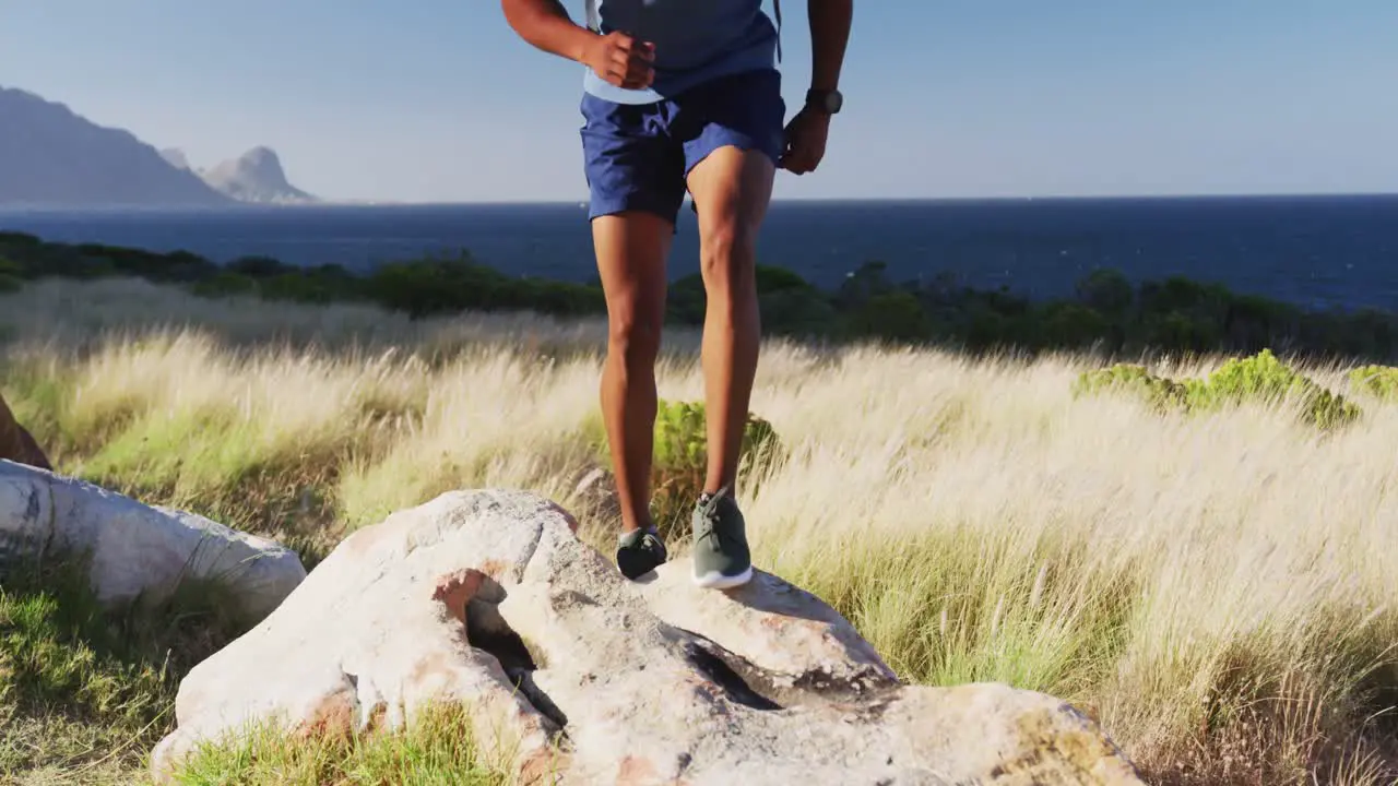 African american man exercising outdoors jumping on a rock in countryside on a mountain