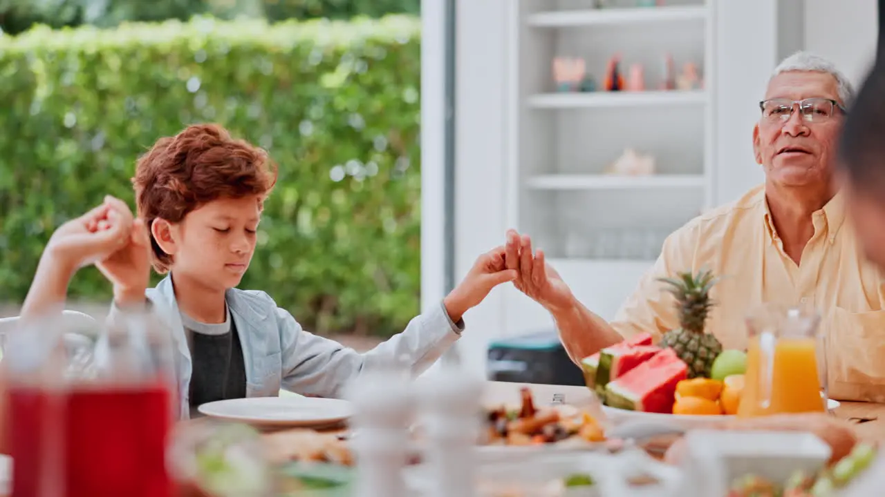 Family holding hands and praying at lunch