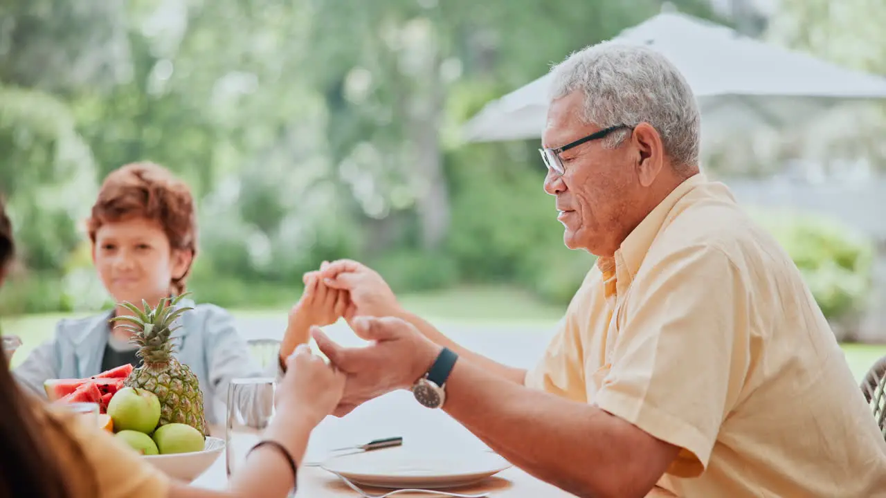 Family holding hands and praying with food