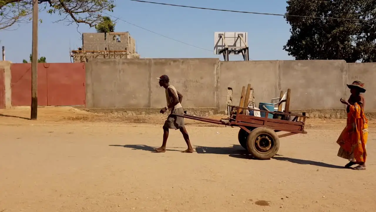 African man pulling cart along dirt road in Madagascar