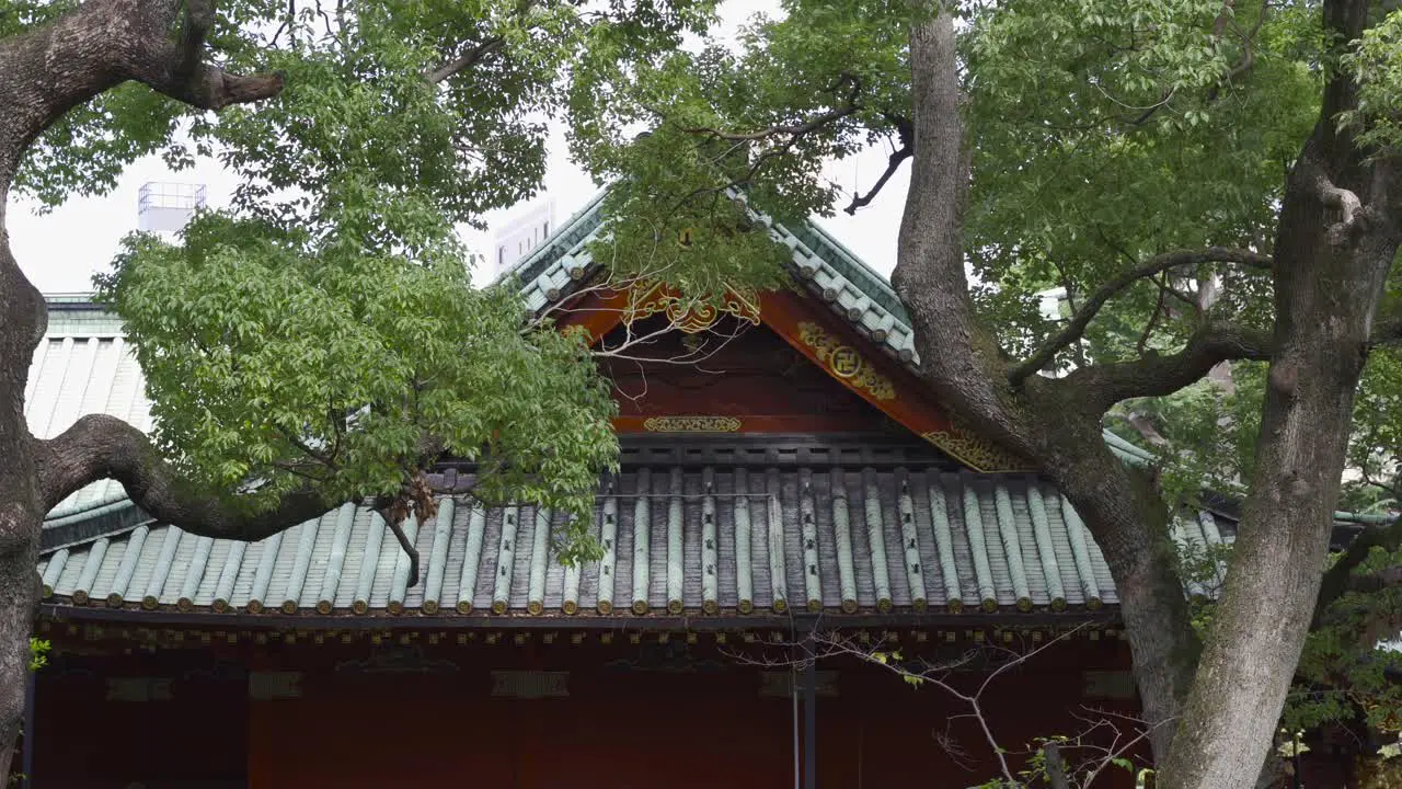 Beautiful Japanese Temple flanked by green trees blowing in strong wind