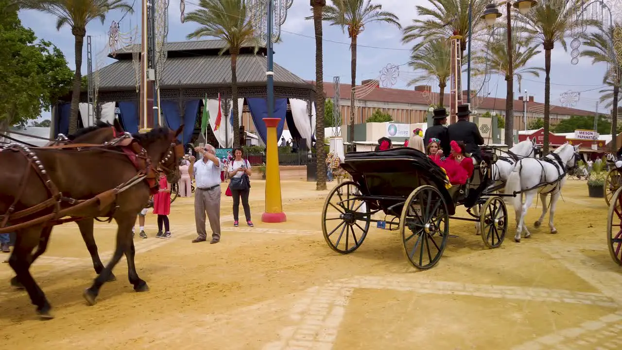 Horses pull carriages of Spanish people in traditional flamenco outfits at Fair