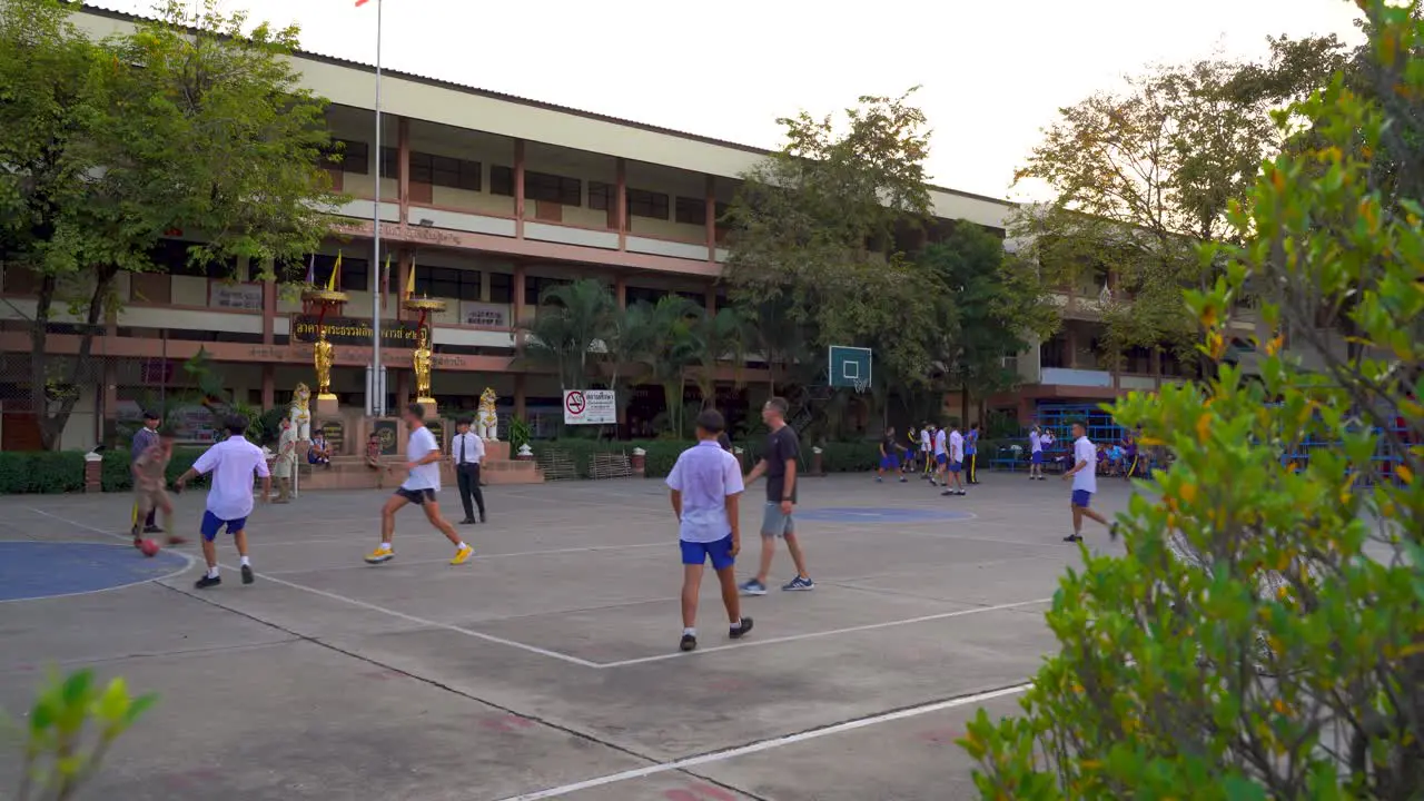 Foreigners playing football with Thai school children at school ground