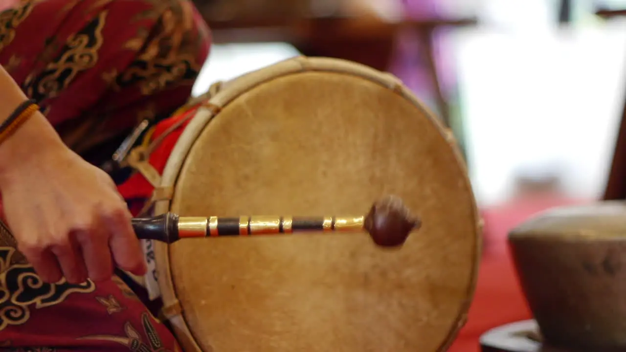 Traditional south east Asian skinned drum played with wooden mallet filmed as close up in handheld style