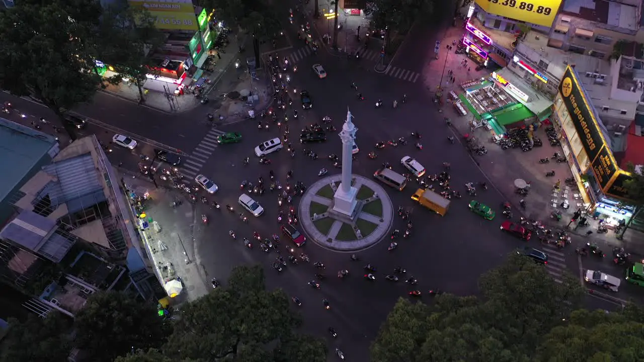 Traffic roundabout at night from drone descending between trees