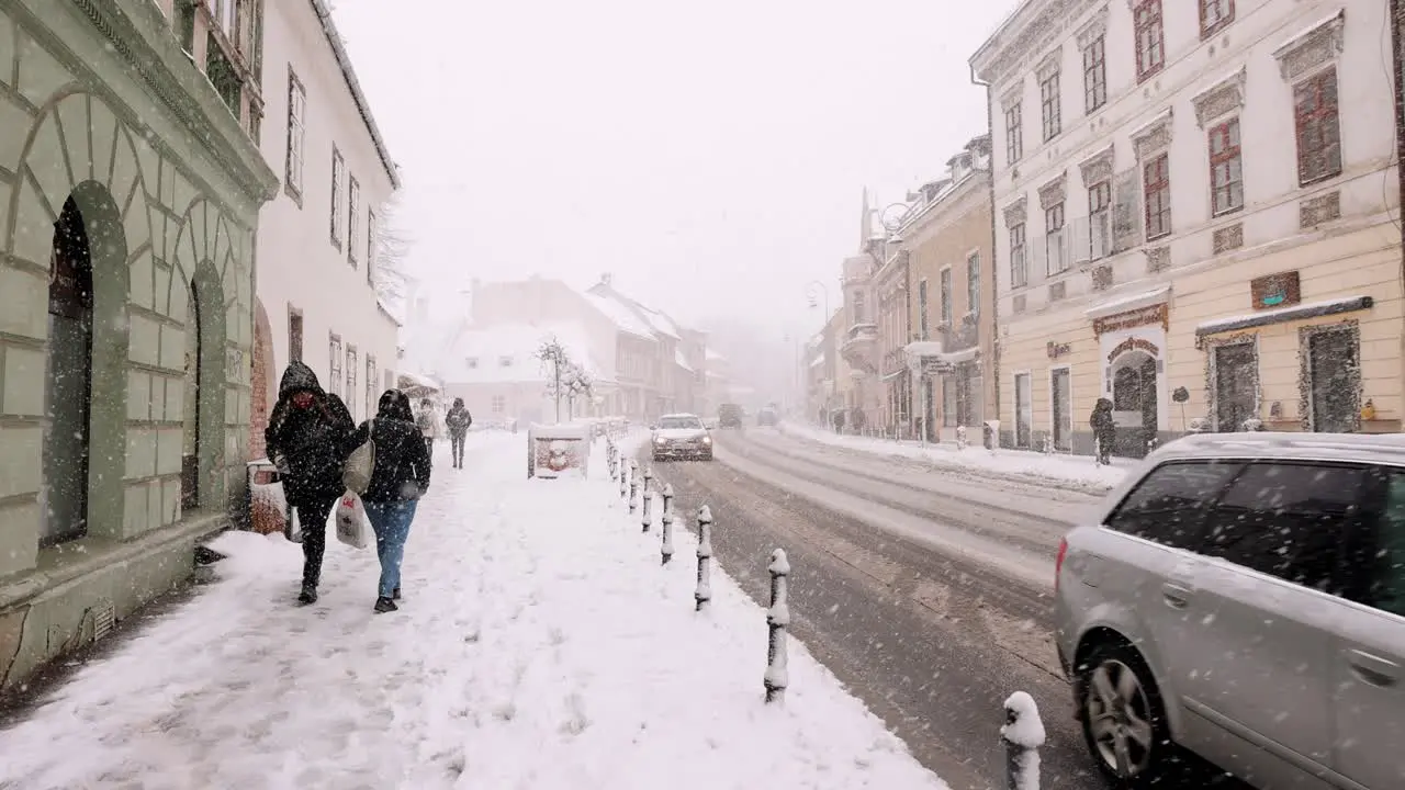 People Walking On The Side Streets Of Brasov Old Town During Snowfall In Transylvania Romania