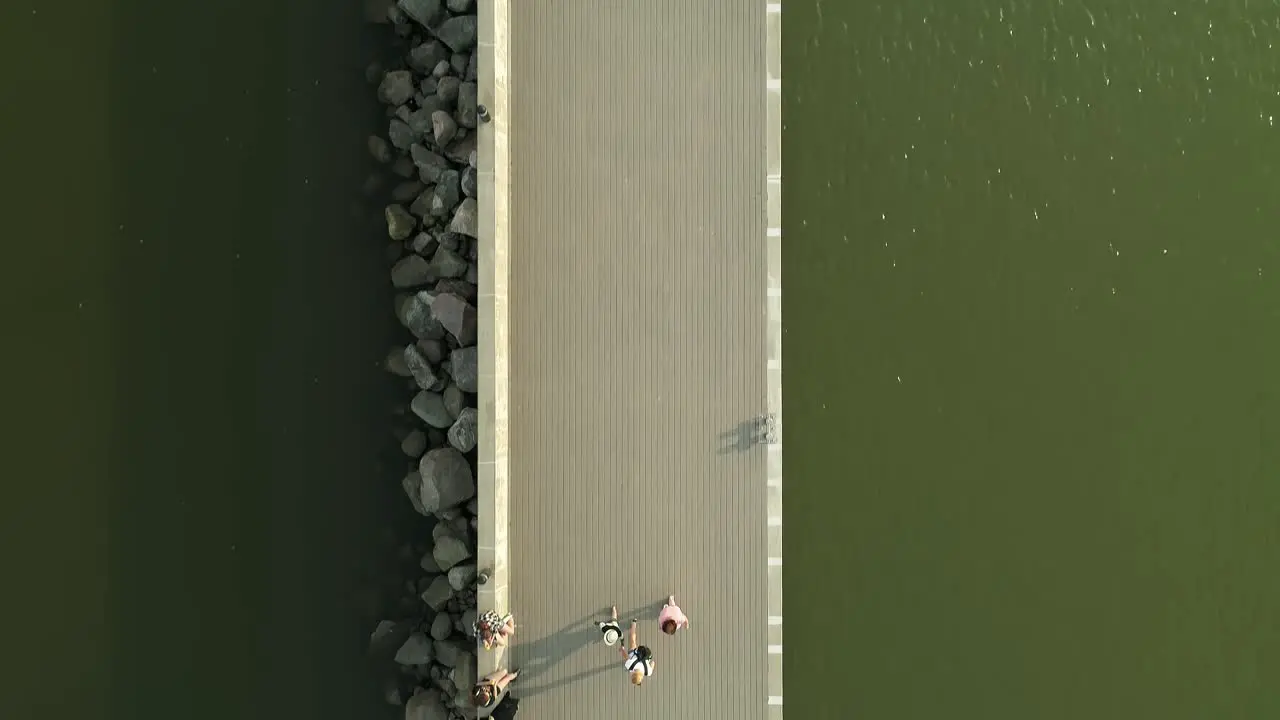 People walk on pier in sunny day