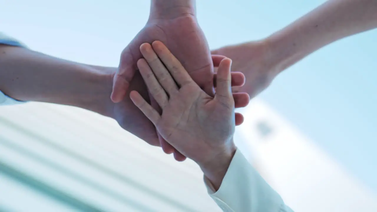 Five people lay their hands on each other as sign of business connection and cohesion concept end of a successful year