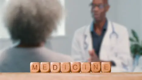 Medical Concept With Wooden Letter Cubes Or Dice Spelling Medicine Against Background Of Doctor Talking To Patient