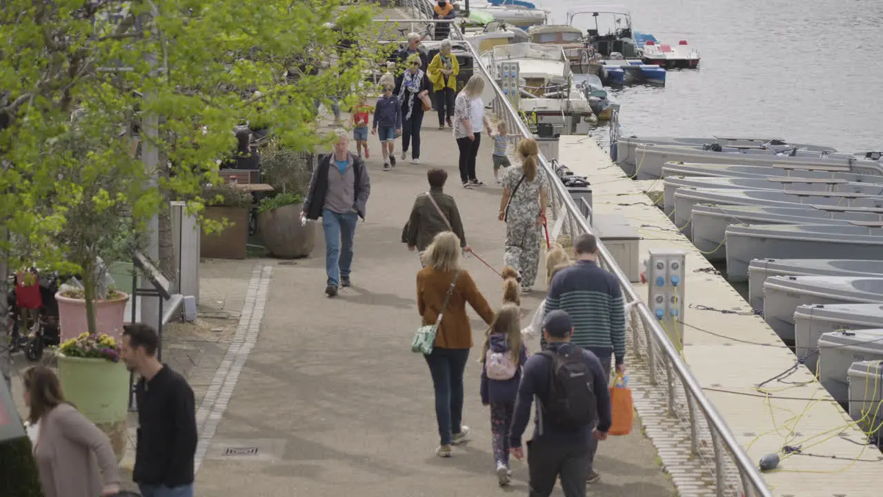 People enjoy beautiful day walking near Thames river in London slow motion view