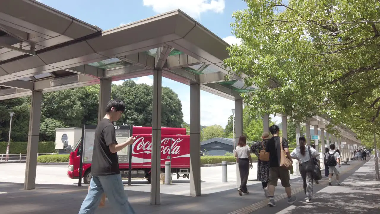 Japanese People Walk in Summer at Kokusaikaikan Subway Entrance Kyoto Japan Next to a Coca Cola Truck