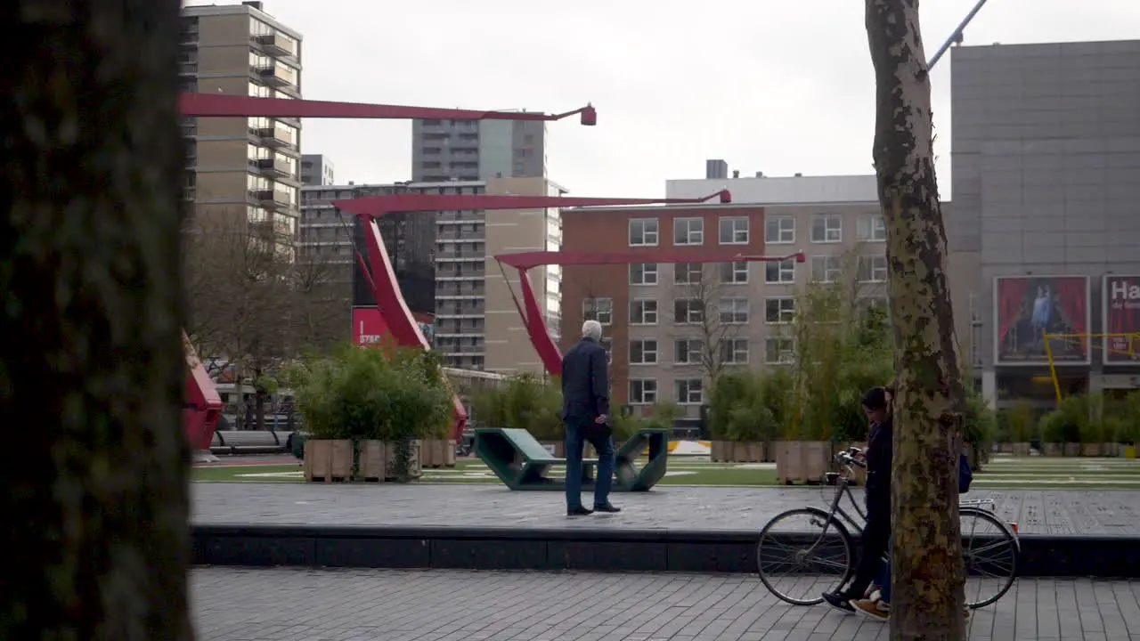 Mother and daughter pushing a pram as an elderly gentleman walks past in Theatre Square Schouwburgplein