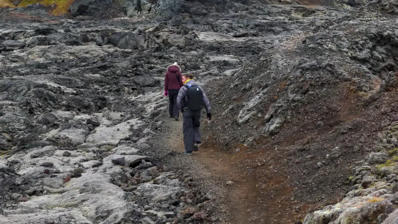 Two people climbing up a volcanic trail scenic rocky landscape in Iceland