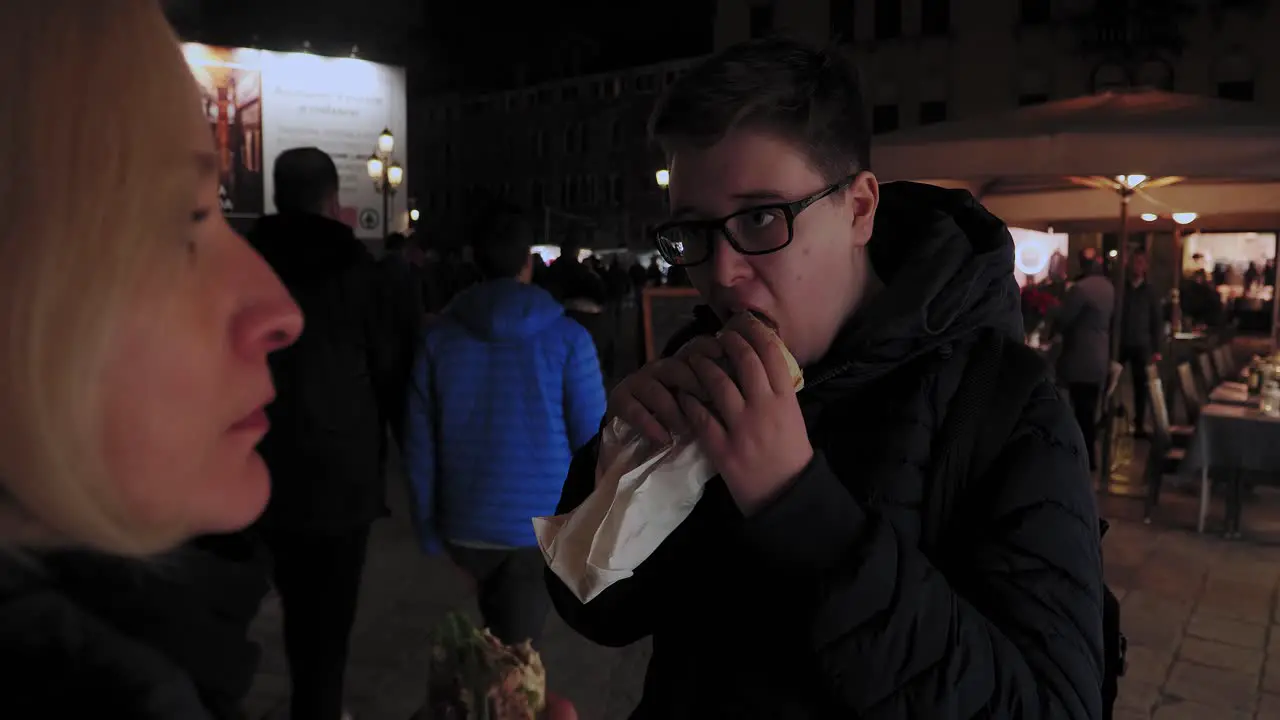 Mother and Son Eat Italian Sandwiches on Busy Street Market in Venice Italy