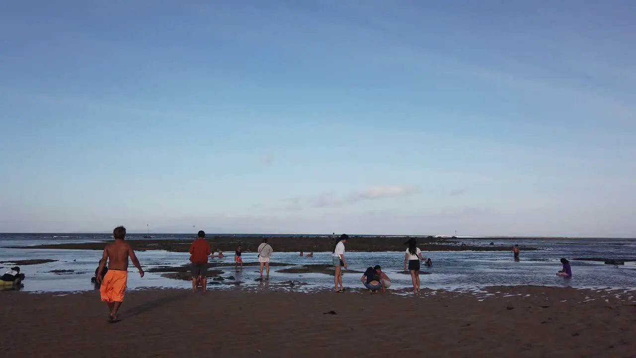 Indonesian People Relax at Low Tide Sea Beach in Sanur Bali Skyline Islets and Natural Atmosphere