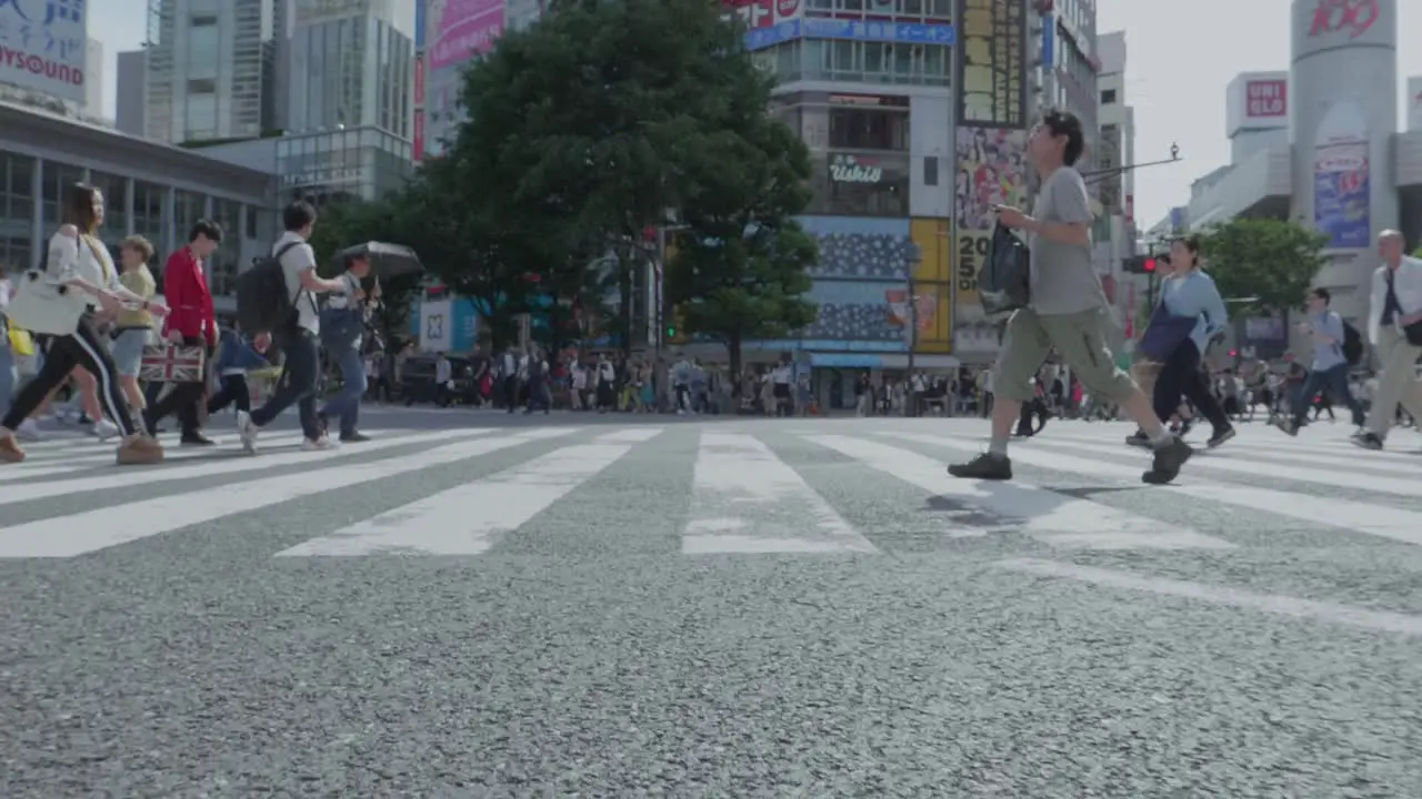 a huge intersection in Tokyo Japan where people cross the street on a sunny day