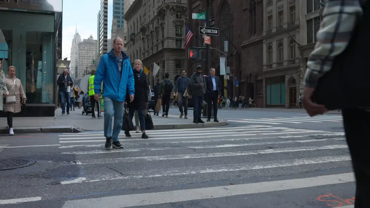 People crossing crowded street of Manhattan in New York City with car and bus traffic on rush hour