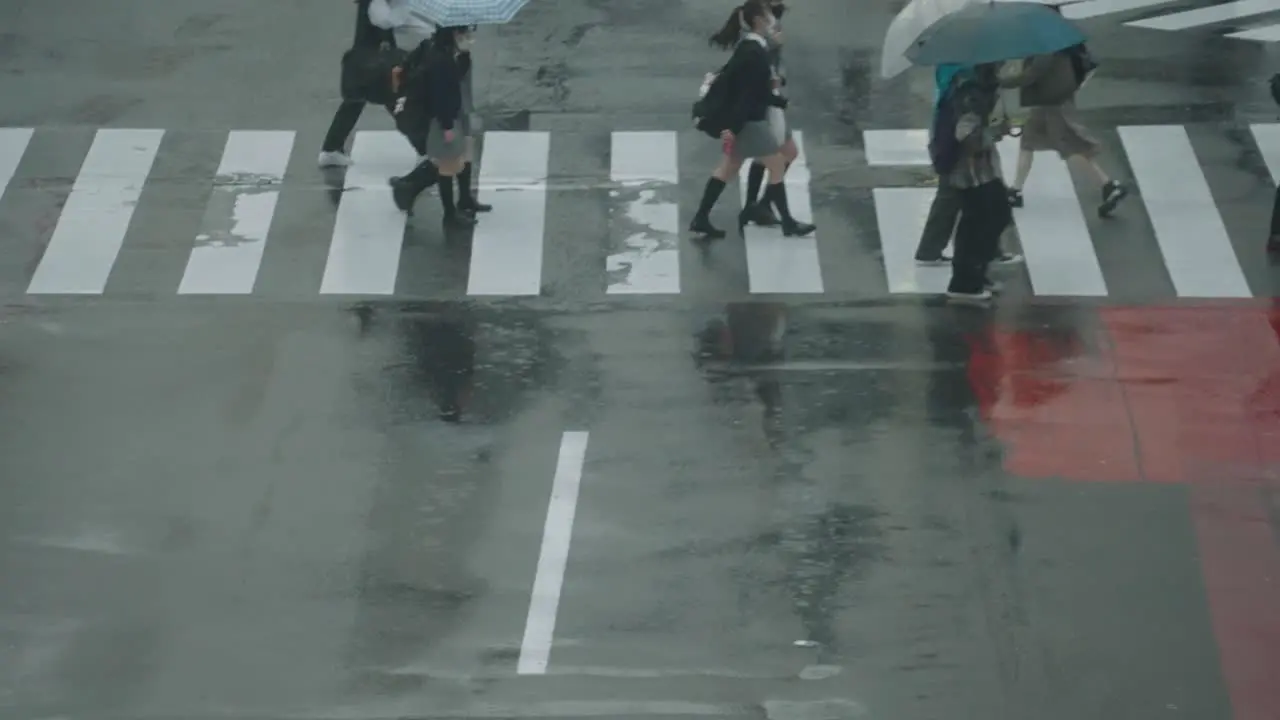 People And Students Walking Across With Reflection On Wet Road In Shibuya Crossing Tokyo Japan On Rainy Day