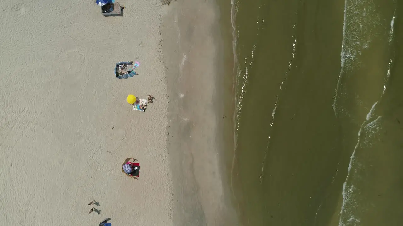 People on beach of Baltic sea coast bath and sunbathe