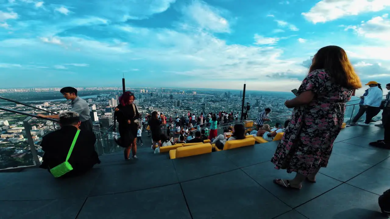 wide view of people relaxing on rooftop terrace with overlooking the city at sunset view