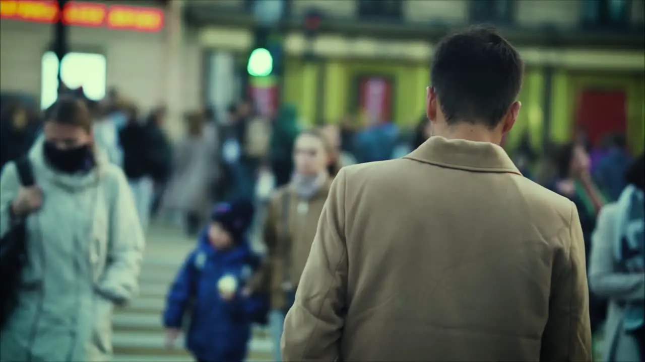 A young attractive man is crossing the road in a crowded place with strangers in the evening