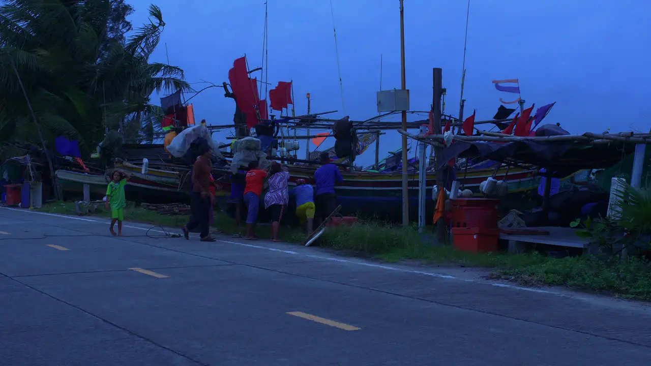 Group of people pushing traditional Thai wooden boat on the shore in strong winds Songkhla Thailand